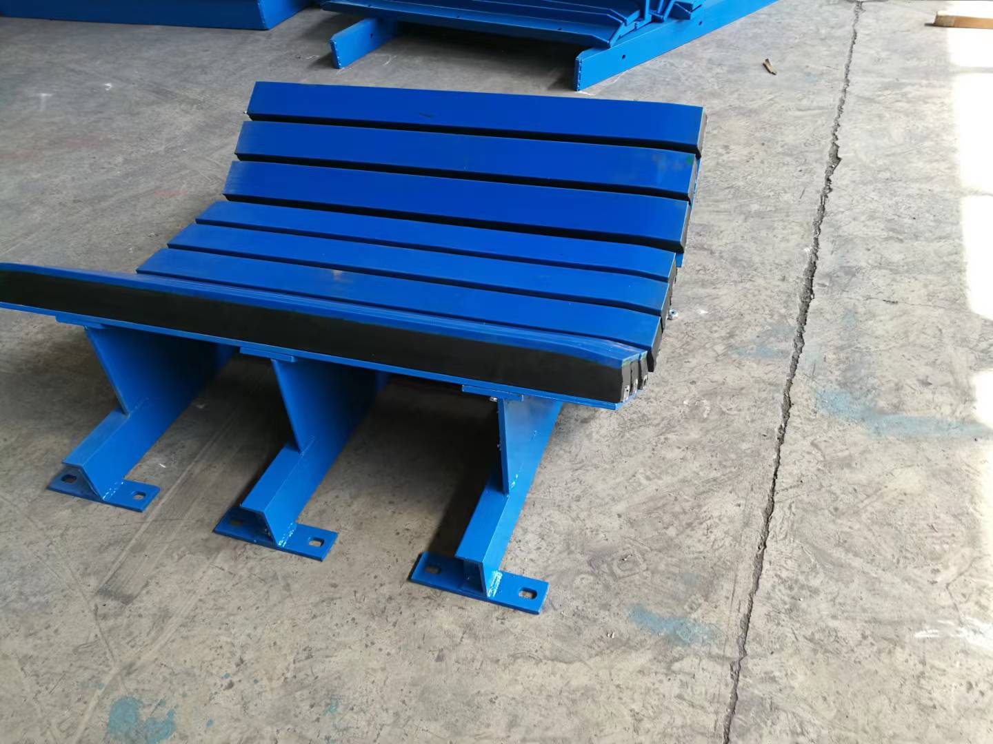 Blue impact support assembly with longitudinal bars and mounting feet visible on the floor