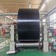 Black nylon conveyor belt roll positioned on industrial belt handling equipment