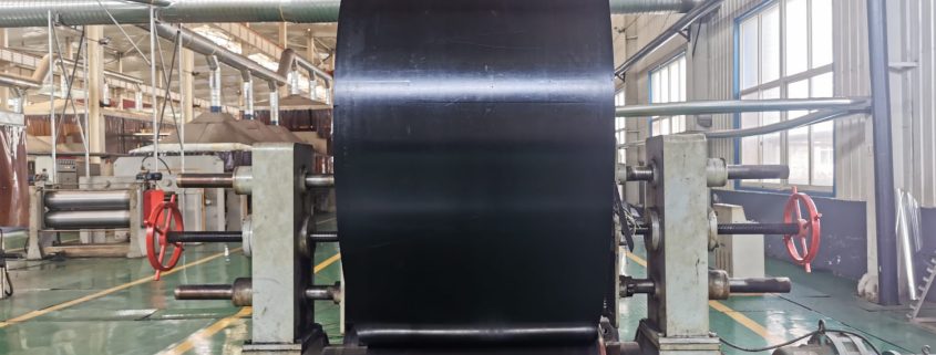 Black nylon conveyor belt roll positioned on industrial belt handling equipment